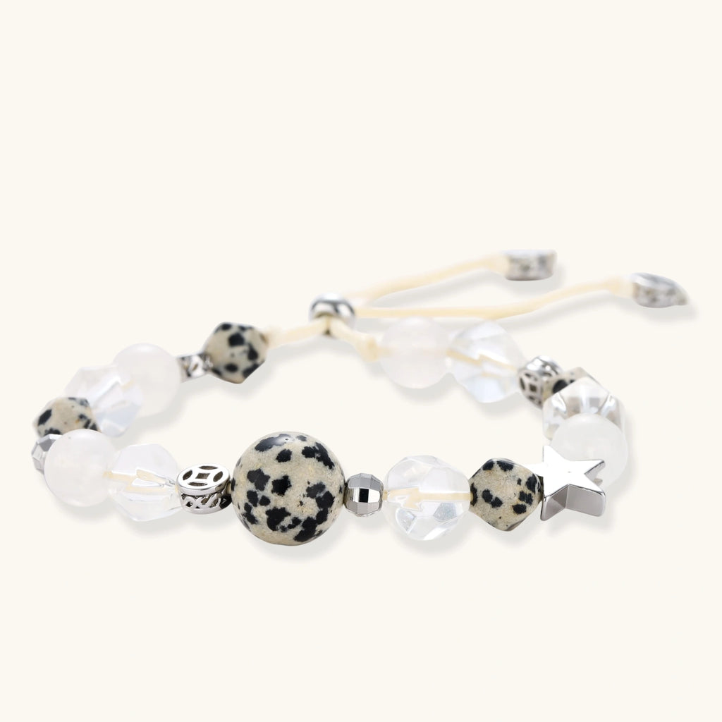 Adjustable beaded bracelet with spotted dalmatian stones, clear quartz crystals, and silver star charm on white background.