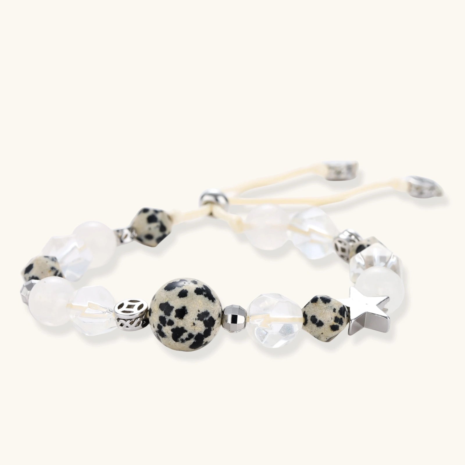 Adjustable beaded bracelet with spotted dalmatian stones, clear quartz crystals, and silver star charm on white background.