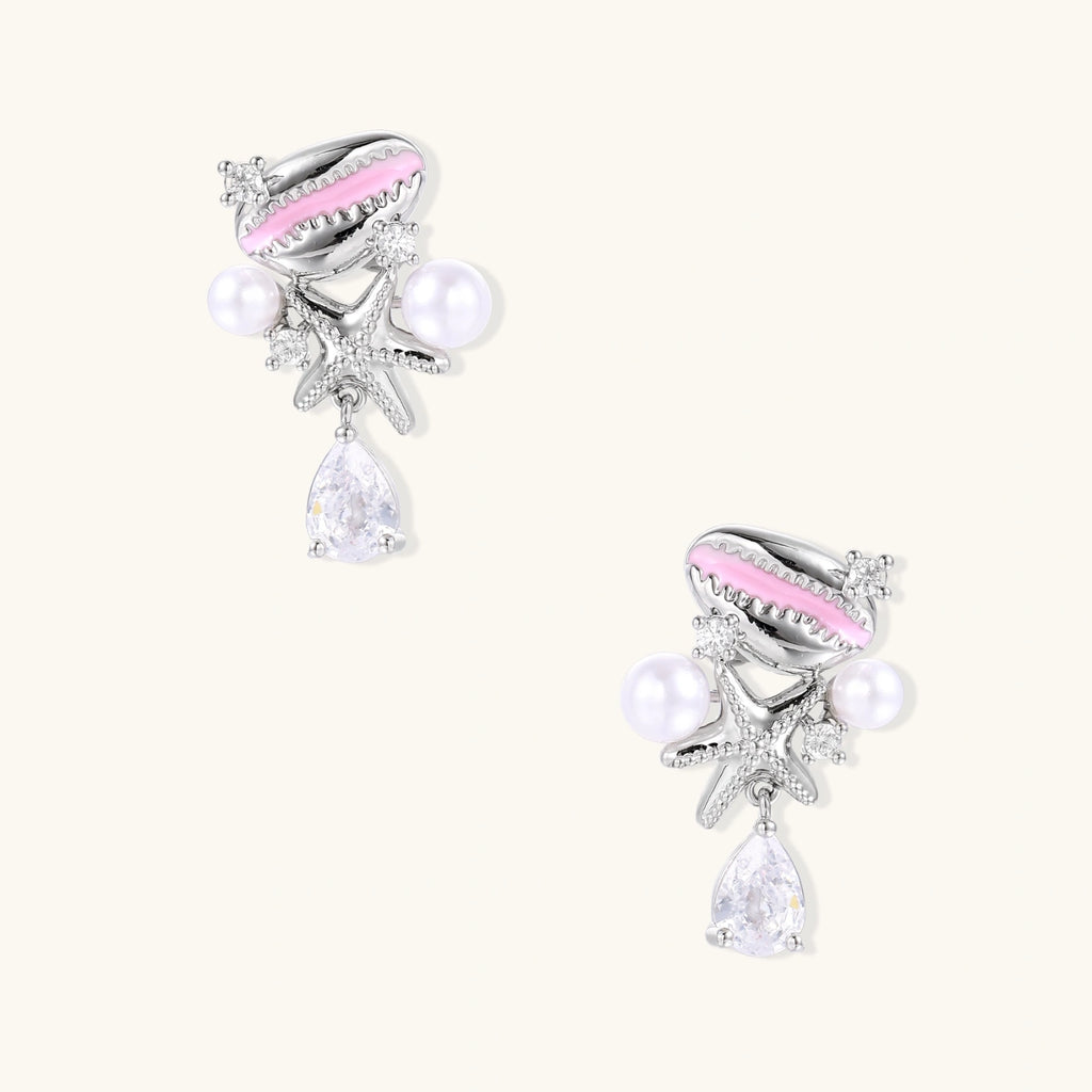 Dainty white gold plated starfish earrings with pink enamel, white pearls, and teardrop crystals on light background.